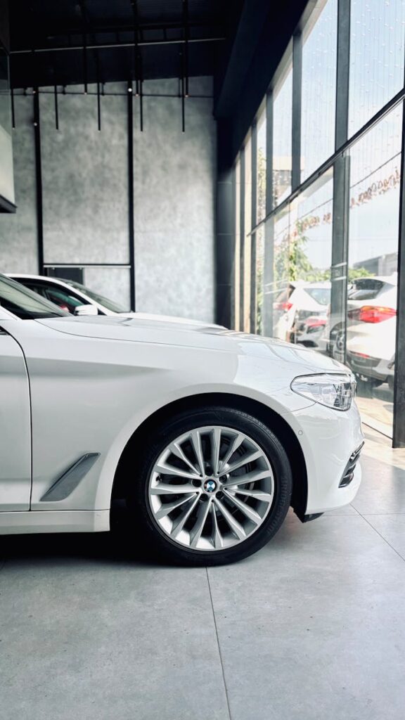 Close-up of a white luxury car in a modern showroom, highlighting sleek design and premium appeal.